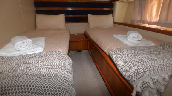 The twin bedroom on the motor yacht Act features two comfortable beds and large windows.